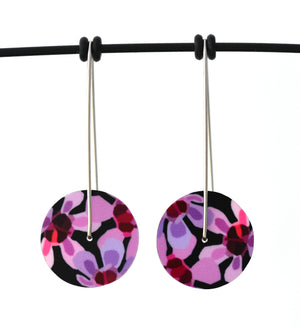 Circle earrings featuring pink Geraldton Wax flowers on a black background. The aluminium earrings discs are approximately 26mm in diameter and the surgical stainless steel drop hooks are approximately 40mm in length.