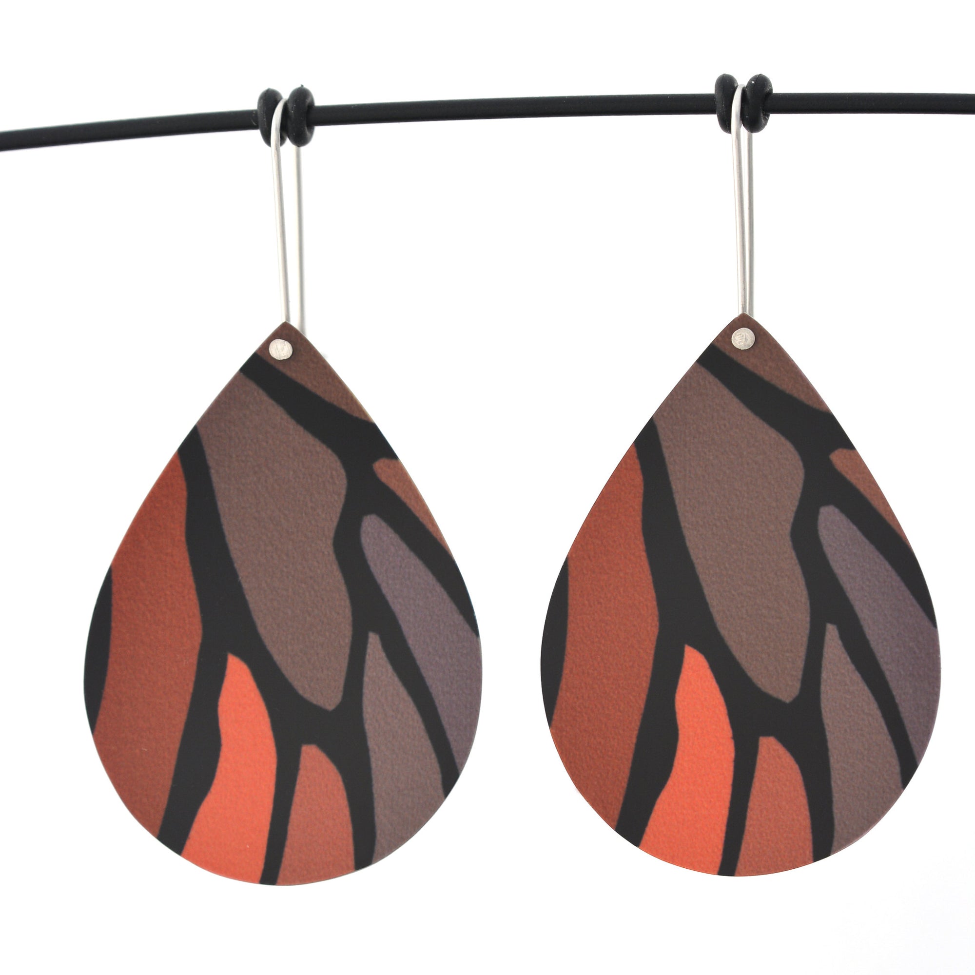 Droplet earrings featuring details from a monarch butterfly wing. The aluminium earrings are approximately 40mm long and 29mm wide. The 15mm long shepherds hooks are surgical stainless steel.