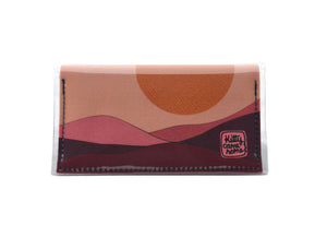 This is an image of the front of a Kitty Came Home bifold mini purse clutch in the 'Moonage daydream' design by Satin and Tat. A golden sun above a burgundy landscape. This is the small size.