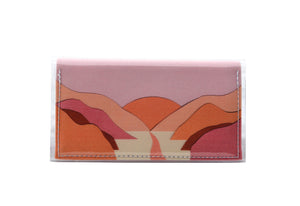 This is an image of the rear of a Kitty Came Home bifold mini purse clutch in 'The golden dawn' design by Satin and Tat. A path wends through a valley of pink and orange hills towards an orange rising sun. This is the small size.