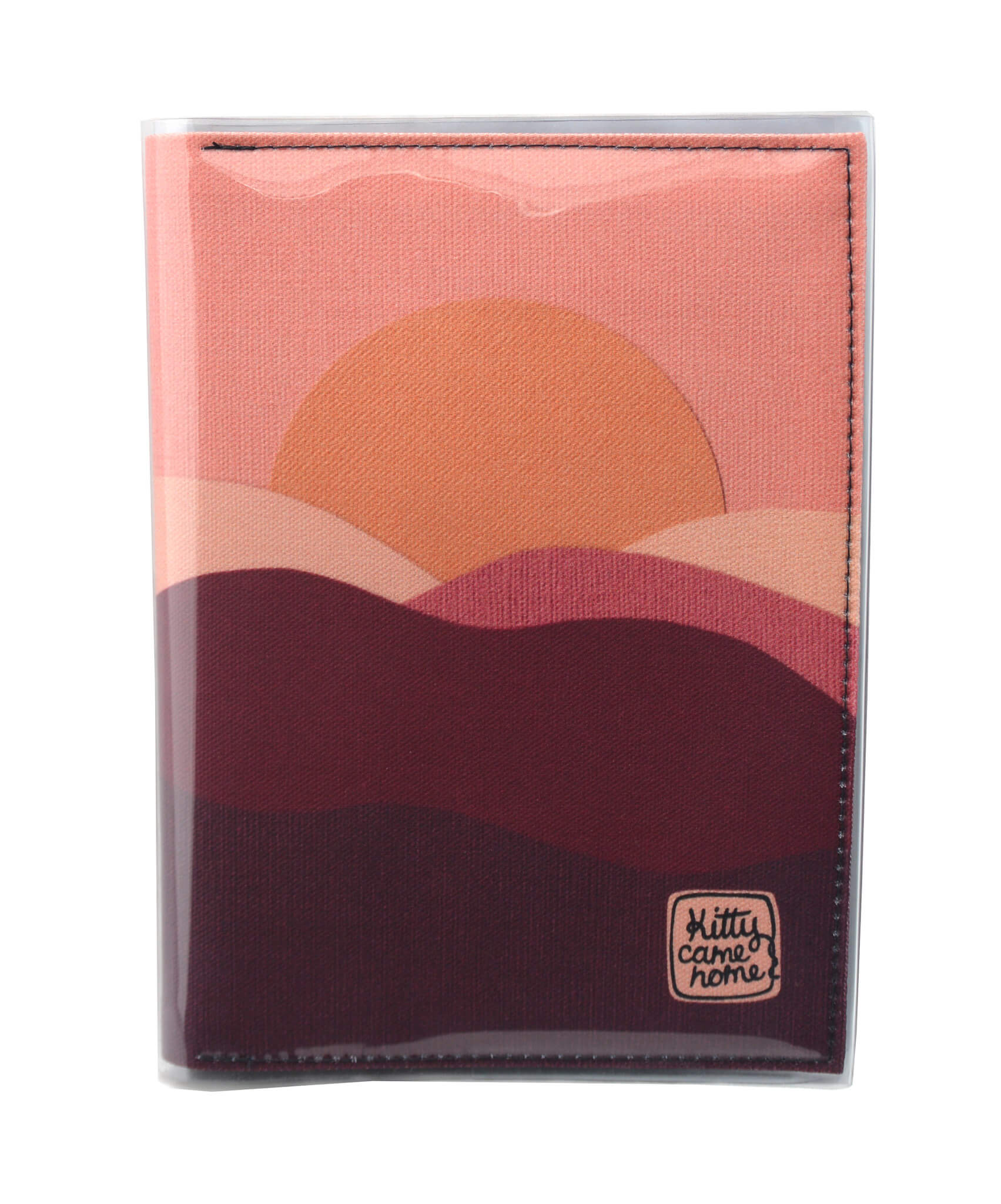 This is an image of the front of a Kitty Came Home A5 journal in 'The night comes down' design by Satin and Tat. An orange sun in a pink sky sinks behind a pink and magenta landscape of rolling hills.