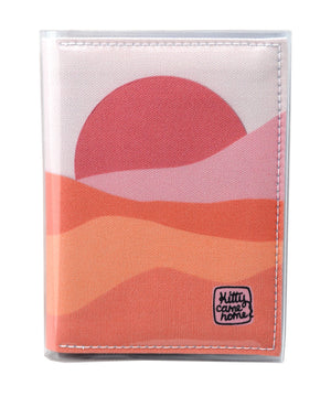 This is an image of the front of a Kitty Came Home A6 journal in the 'Waiting for the sun' design by Satin and Tat. A warm pink sun rises over a landscape of pink hued sands.